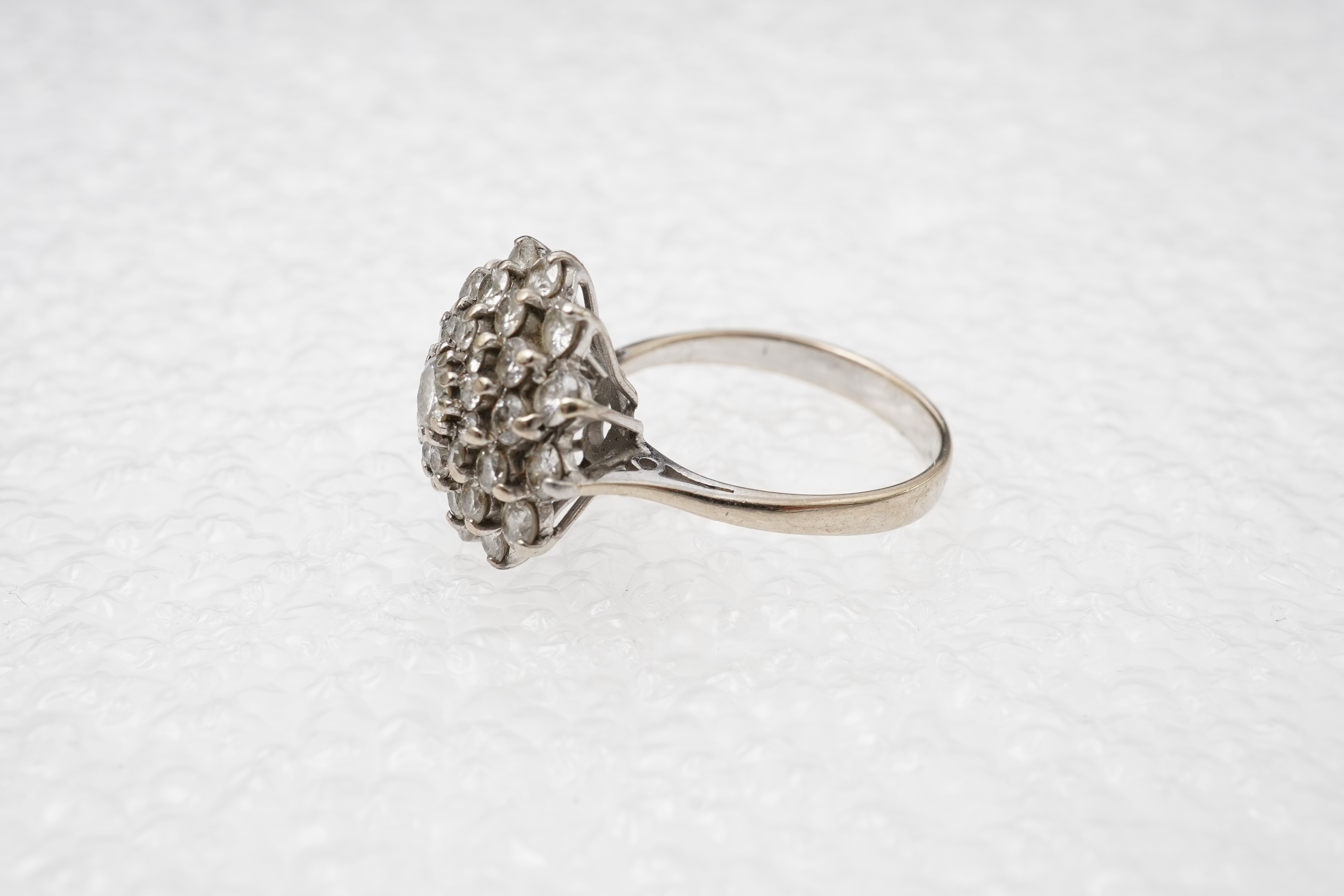 A white gold and diamond cluster ring, set with a concentric arrangement of brilliant-cut diamonds totalling approximately 1.50 carats, size M, gross weight approximately 5 grams